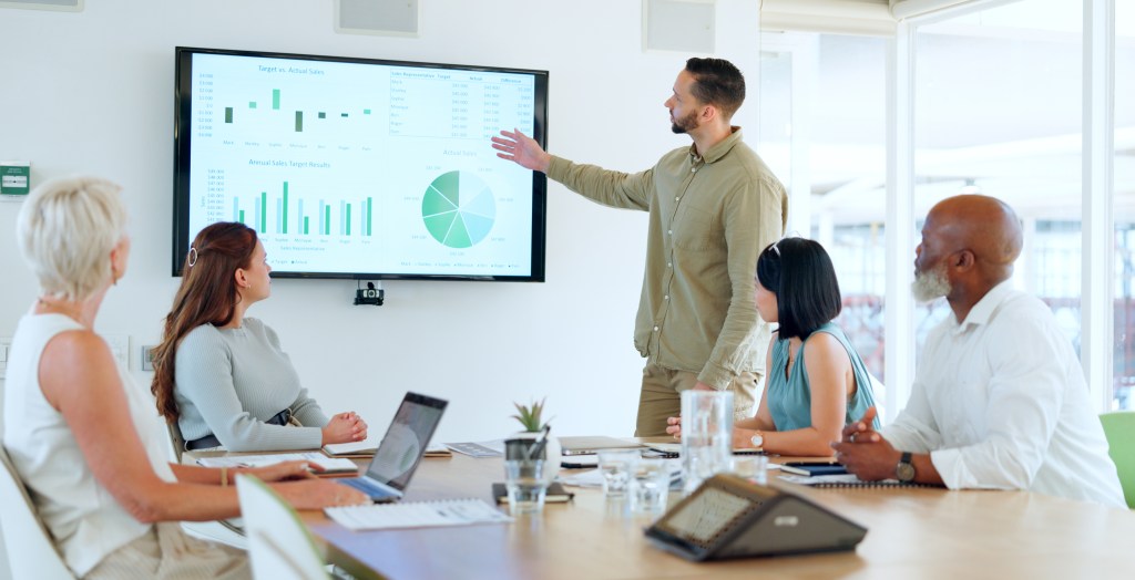 Business professional presenting data charts during a team meeting in a modern office.